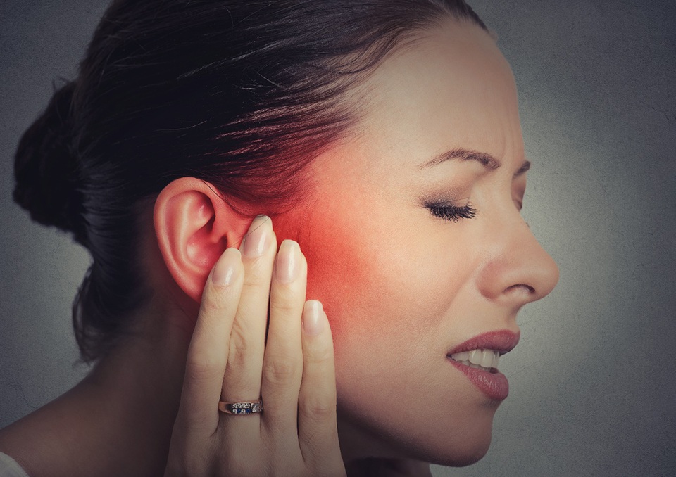 Woman with TMJ dysfunction holding cheek
