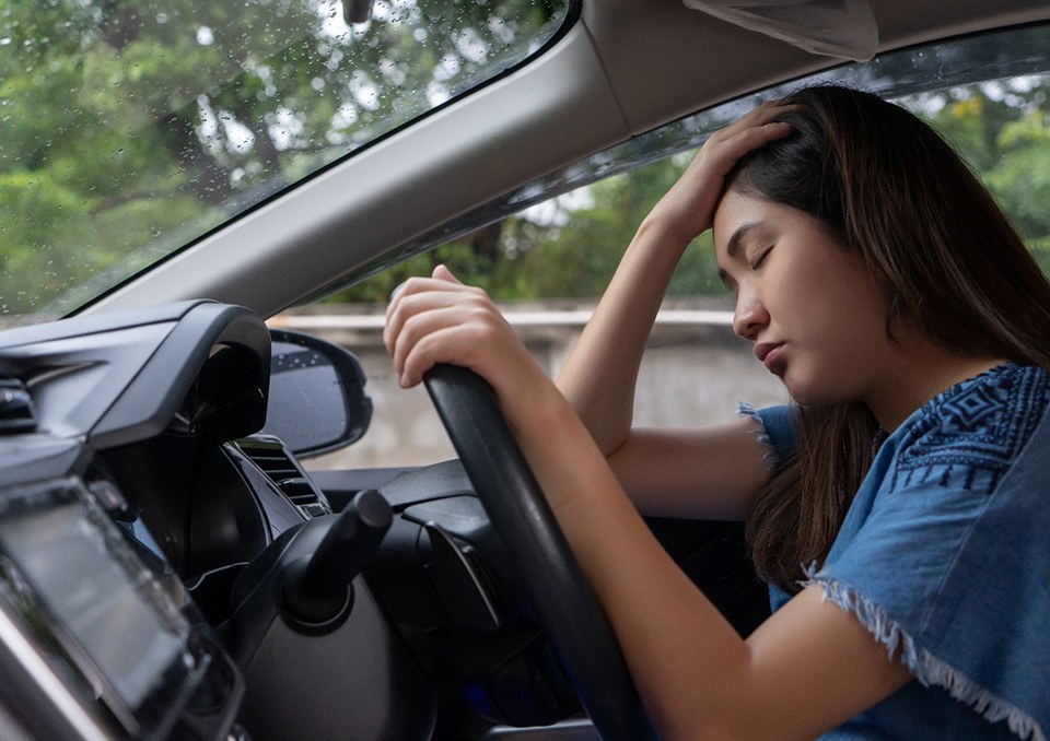 Woman driving while drowsy, suffering from dangers of sleep apnea