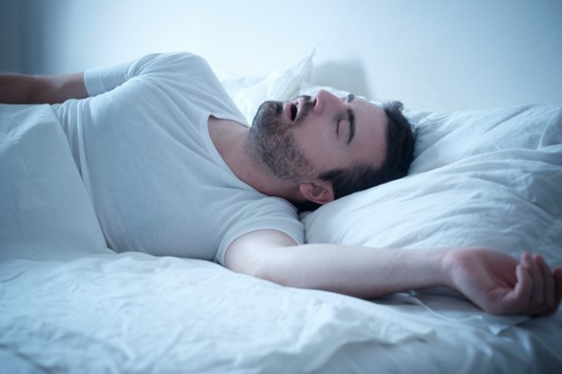 Man with sleep apnea snoring in bed.