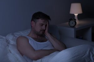 Sleepless man sitting up in bed